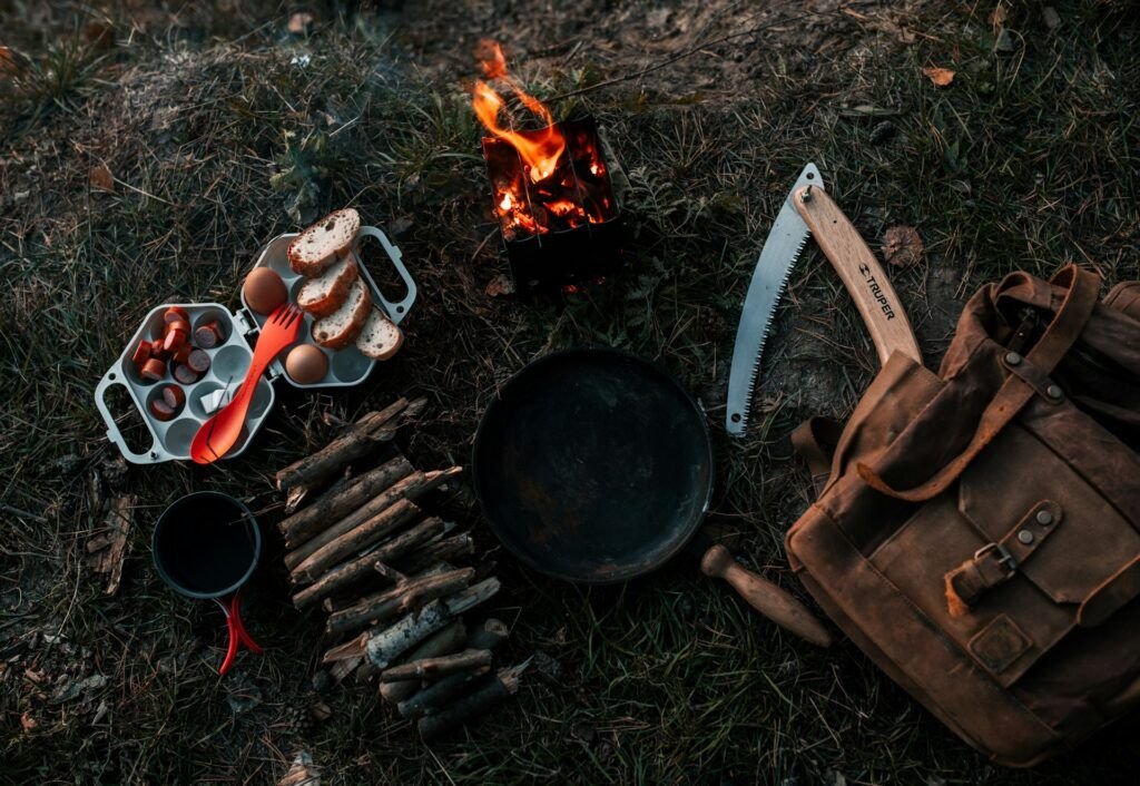 Camper preparing food on portable stove at campsite with organized cooking setup