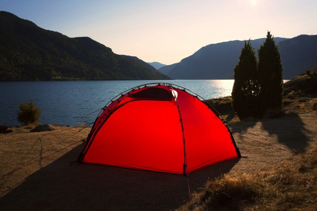 Peaceful forest campsite with tent set up near a lake at sunrise