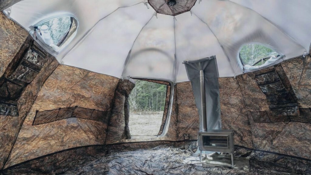 Interior view of the Russian Bear Hot Tent showing cots and a wood stove.