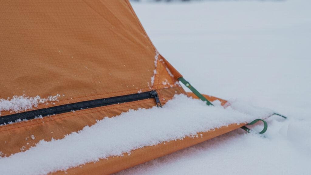 Snow skirt on a winter tent piled with snow to prevent drafts.
