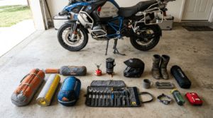 The image is motorcycle camping checklist items spread across the floor in the bike garage