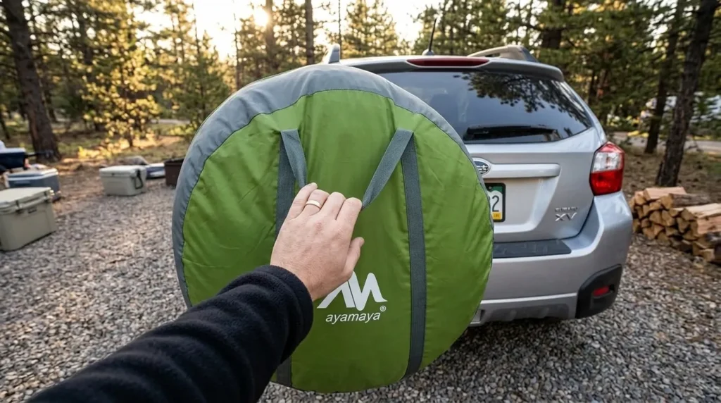 A person holding the large circular carrying bag of an Ayamaya pop up tent to show its dimensions for car storage.