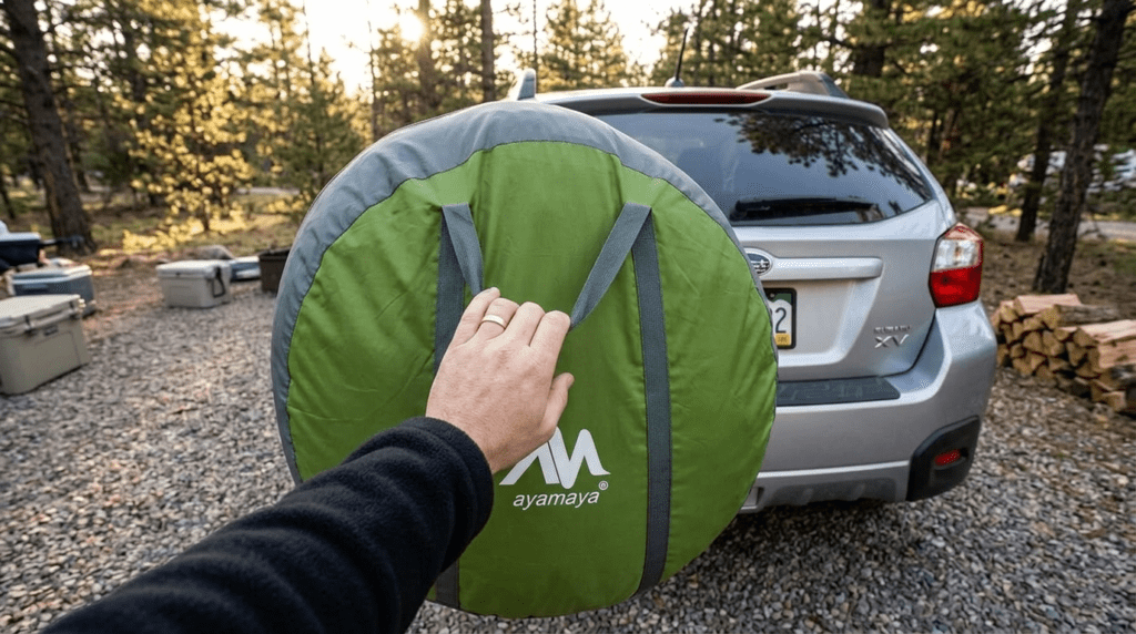 A person holding the large circular carrying bag of an Ayamaya pop up tent to show its dimensions for car storage.