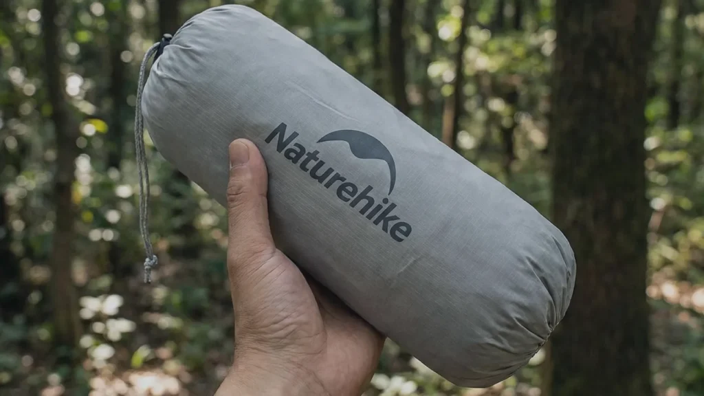 Hand holding the small packed bag of the Naturehike Cloud Up 1 tent.
