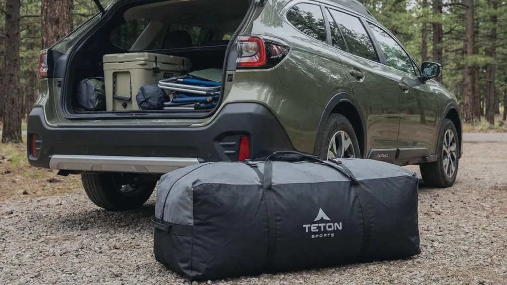 The Teton Mesa canvas tent packed in its carry bag next to a car trunk for size comparison.
