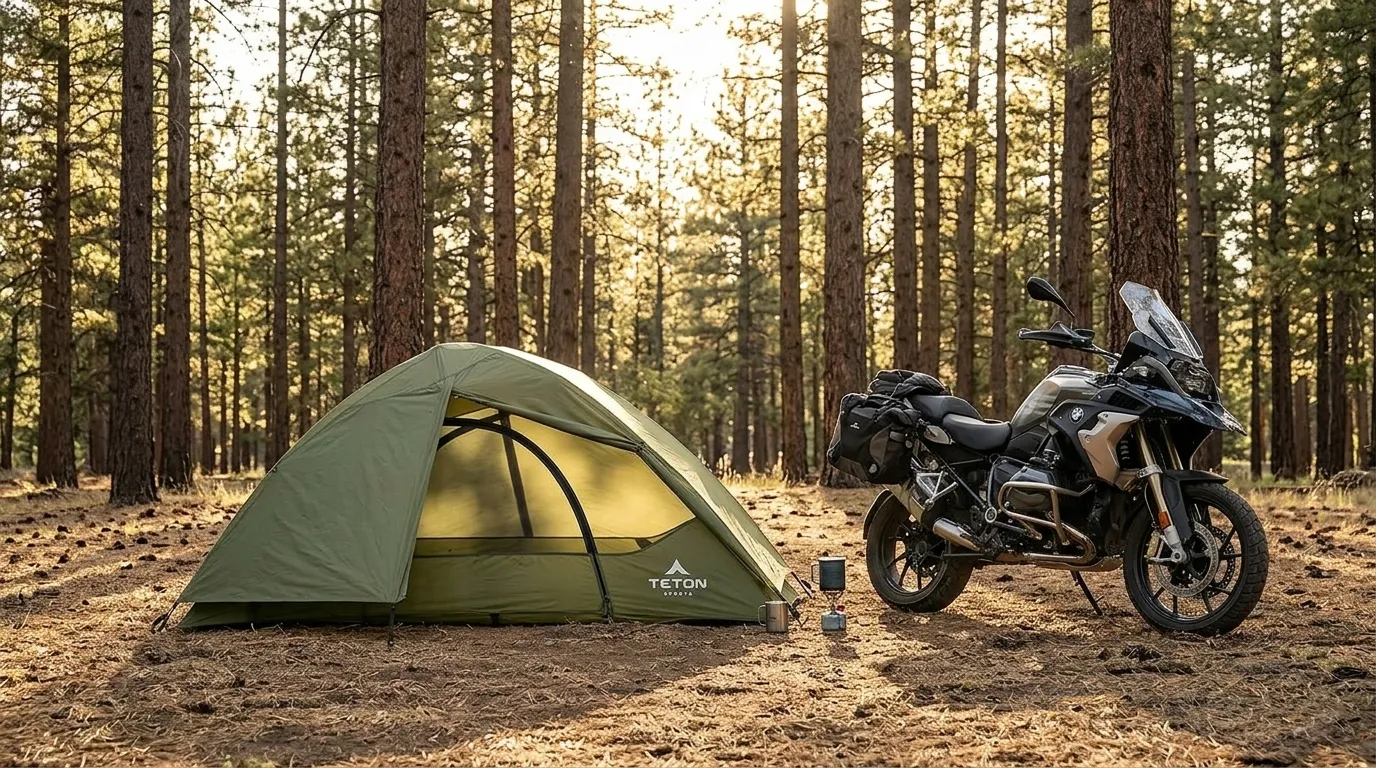 A TETON Sports Vista Quick Tent pitched in a forest clearing next to a motorcycle at sunset.