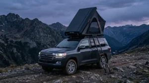 A San Hima hard shell rooftop tent set up in the rain on an adventure vehicle.
