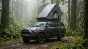 A vertical hard shell Vevor rooftop tent set up on an SUV in a foggy forest.