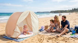 A high quality baby beach tent pitched on a sunny beach with a family in the background.