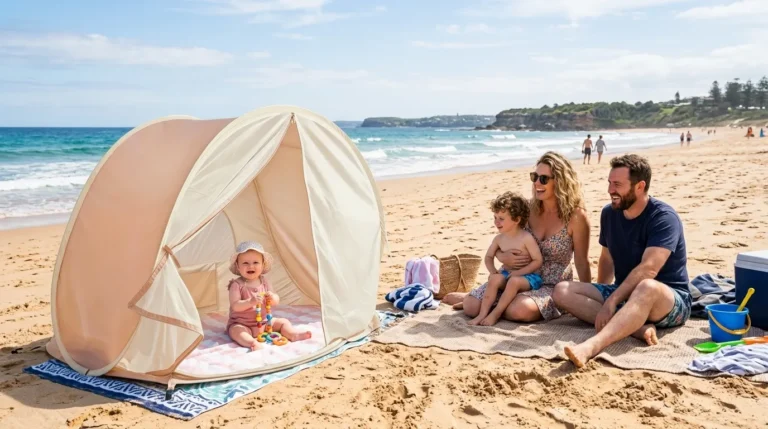 A high quality baby beach tent pitched on a sunny beach with a family in the background.