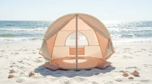 A cream-colored Pivoryla baby beach tent set up on a sunny beach for infant protection.