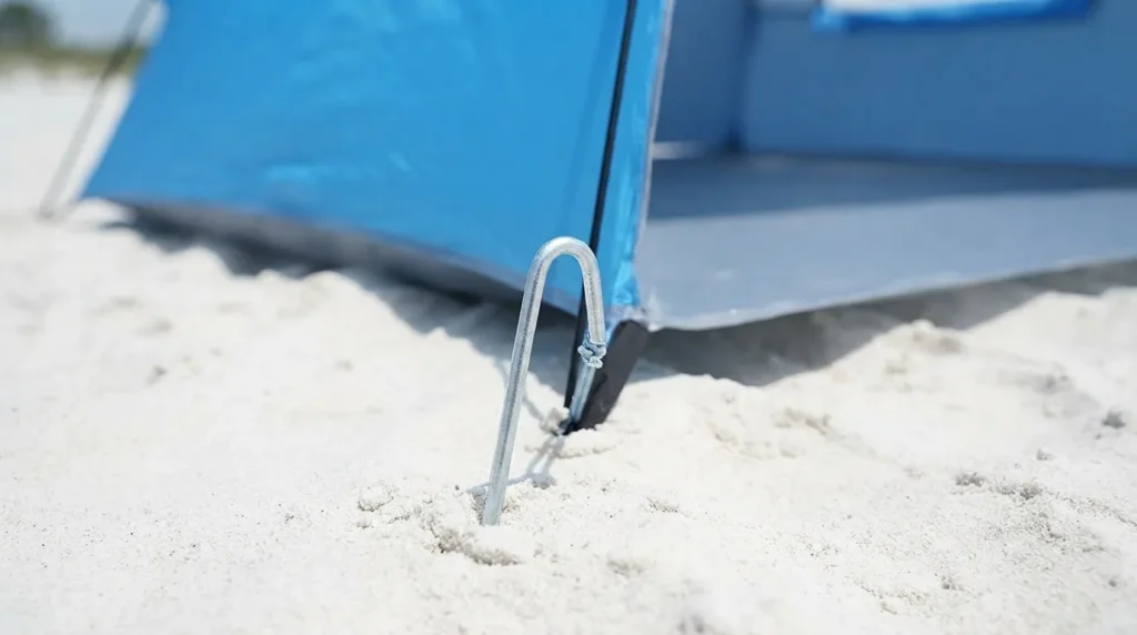 Steel stake and sandbag anchoring a Camel Crown beach tent against wind