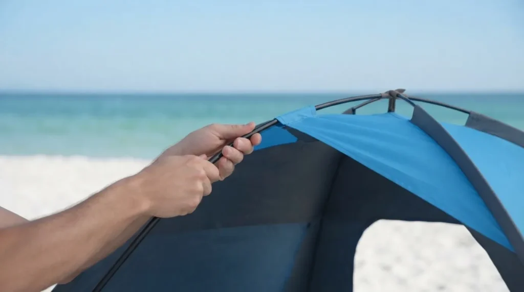 Threading a fiberglass pole through the sleeve while setting up a beach tent