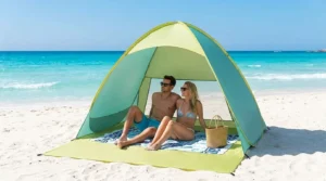 Two adults sitting inside an automatic pop up beach tent on the sand