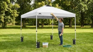 Cleaning an Eagle Peak pop up canopy tent with a soft brush, bucket, and garden hose in the shade